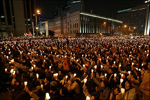 서울시의회앞에 모인 시민들이 촛불을 들고 있다. 뒷편으로 서울시청과 플라자 호텔이 보인다. 